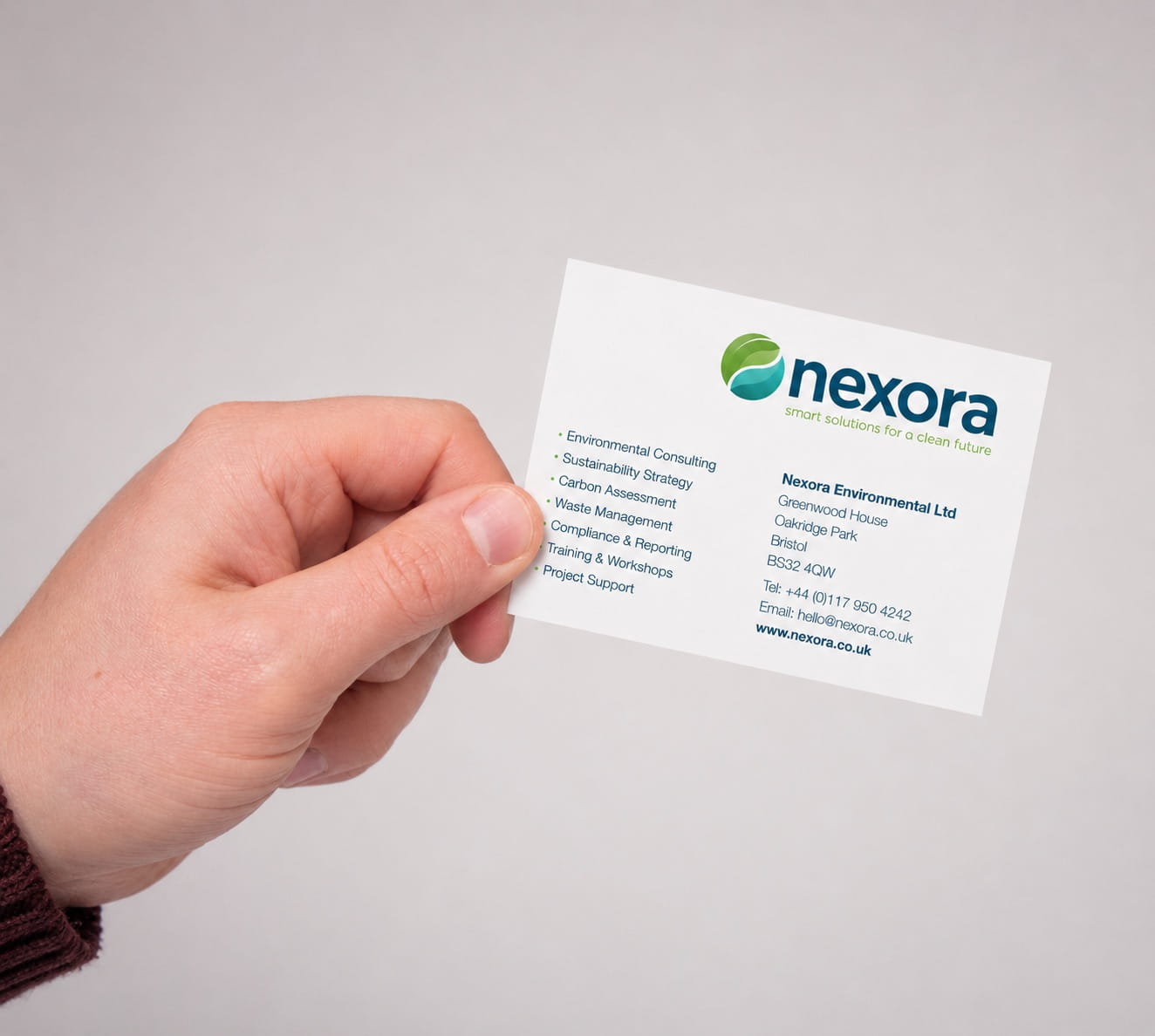 Corporate business card held in hand against a light grey background